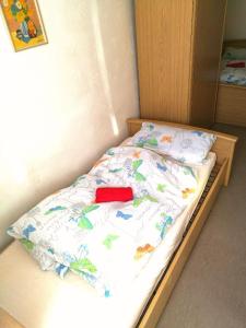 ein Bett mit einer weißen Bettdecke mit einem roten Objekt darauf in der Unterkunft Pension Engel in Pfullendorf