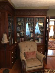 a living room with a chair and book shelves at Penley House Bed & Breakfast in Auburn