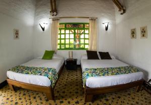 two beds in a room with a window at Hotel La Coqueta in Montenegro