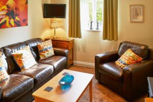 a living room with two leather couches and a coffee table at Farthing Cottage in Norwich