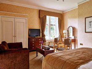 a hotel room with a bed and a television at Dumbleton Hall Hotel in Broadway