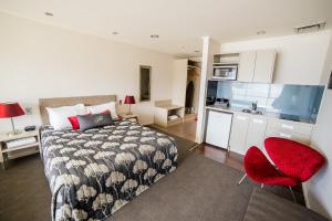 a bedroom with a bed and a red chair at Marakura Deluxe Motel in Te Anau
