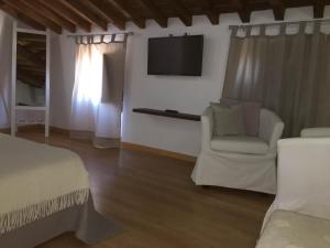 a bedroom with a bed and a chair and a television at Refúgio da Vila in Monsaraz