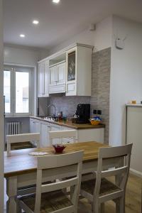 cocina con mesa de madera y armarios blancos en Casa Angela en Campobasso