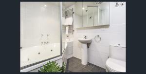 a white toilet sitting next to a bath tub in a bathroom at Waterfront (Yarra St) by Gold Star Stays in Geelong