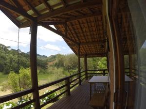 a room with a balcony with a table and a view at Sitio Rosa de Minas in Gonçalves