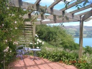 a patio with a table and a bench under a pergola at Mumfords in Akaroa
