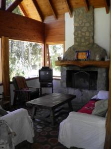 a living room with a stone fireplace and a table at La Casa de Huemul in Villa La Angostura