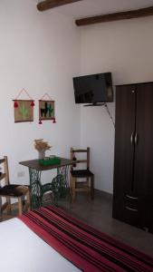 a bedroom with a bed and a table and a flat screen tv at Cabañas Cultura Tafi in Tafí del Valle