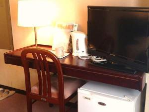 a wooden desk with a television and a chair at Select Inn Hamamatsu Ekimae in Hamamatsu