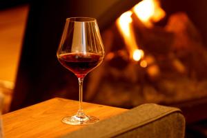 a glass of wine sitting on a table in front of a fireplace at Wakkanupuri in Teshikaga