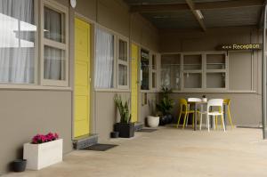 a porch with yellow doors and tables and chairs at 105 On The Park in Bordertown
