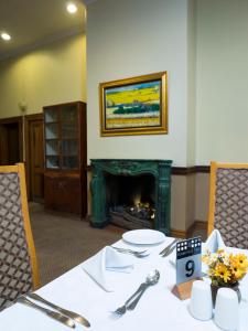 a dining table with a fireplace in a room with a table sidx sidx at The Elegant Lodge Menlo Park in Pretoria