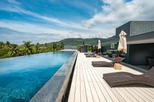 a swimming pool with chaise lounge chairs on a wooden deck at Kamala Resotel, SHA Extra Plus in Kamala Beach