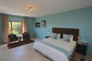 a bedroom with a bed and two chairs and a window at River Crossing Lodge in Windhoek
