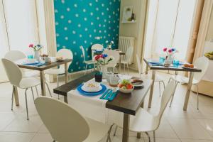 un comedor con sillas blancas y mesas con comida. en Bellini Home B&B, en Catania