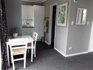 a kitchen and dining room with a white table and chairs at Suite Petite in Taupo