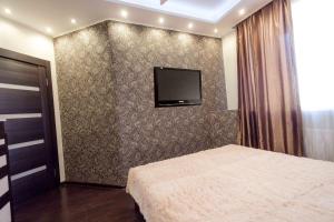 a bedroom with a bed and a tv on a wall at Gazovikov 33 Akvapark Evropeyskiy in Tyumen