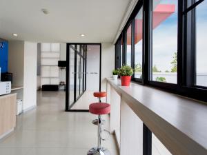 a bar with a red stool in a room with windows at Hop Inn Nakhon Sawan in Nakhon Sawan