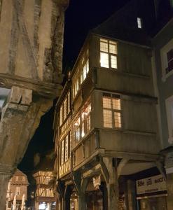un antiguo edificio de madera con luces encendidas por la noche en Ty Clément, en Dinan