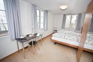 1 dormitorio con sofá, escritorio y ventanas en Bienenberg - Das Genusshotel im Grünen - Liestal, en Liestal