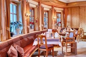 a restaurant with tables and chairs and windows at Habachklause Familien Bauernhof Resort in Bramberg am Wildkogel