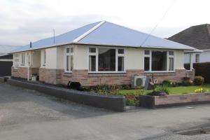 a white house with a blue roof at Rosies Place in Oamaru