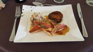 a white plate with food on a table at Logis Hôtel Le pont d'Arcole in Riscle