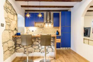 a kitchen with blue cabinets and two bar stools at Apartment Studio-25 in Rijeka