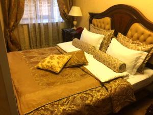 a bed with gold and white pillows on it at Hotel Lux Angliter in Vologda