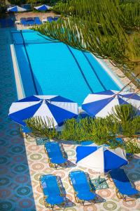 a pool with blue and white chairs and umbrellas at Nontas Apartments in Hersonissos