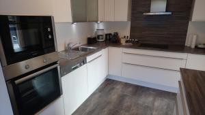 a kitchen with white cabinets and a sink and a microwave at Appartement STOA in Kleinarl