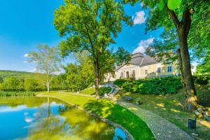 uma casa com um lago em frente em Prónay-kastély em Alsópetény