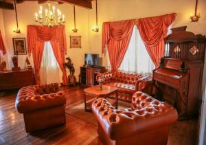 a living room with leather furniture and a piano at Hotel Glendower in Nuwara Eliya