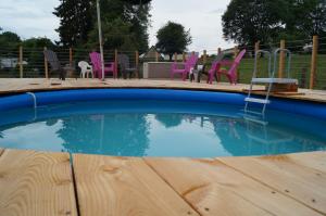 a swimming pool with colorful chairs and chairs in a yard at Gîte de 15 places en chambre de 2, 4, 5 personnes in Saint-Exupéry-les-Roches