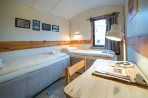 um quarto com duas camas e uma mesa com um candeeiro em Mary-Ann's Polarrigg em Longyearbyen