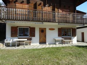 a house with a balcony and a table and benches at Chalet Pinocchio in Mühlebach