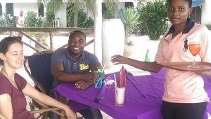 two people sitting at a table with a tray of drinks at Union Beach Bungalow in Nungwi