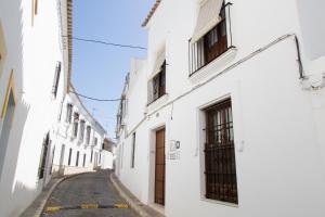 una calle vacía en un callejón con edificios blancos en Casa Rural Migolla, en Osuna