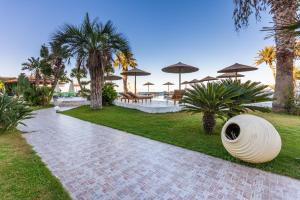 een loopbrug met palmbomen en parasols in een resort bij Alai Beach Resort in Stalida