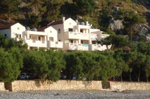 a large white house on a hill with trees at Ravdoucha Beach Studios in Ravdhoúkha