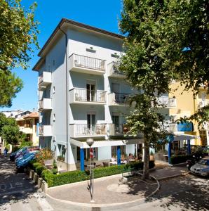 un edificio bianco con un albero di fronte di Hotel Adigrat a Riccione