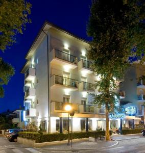 un bâtiment blanc avec un arbre devant lui dans l'établissement Hotel Adigrat, à Riccione