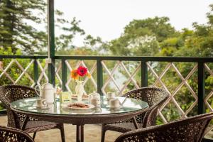 a table with a vase of flowers on a balcony at Fairy Glen in Coonoor