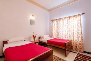 a bedroom with two beds and a window with red sheets at Fairy Glen in Coonoor
