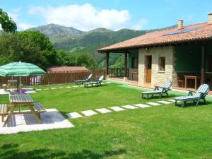 a yard with benches and an umbrella and a house at Coviellador Cangas de Onís in Coviella