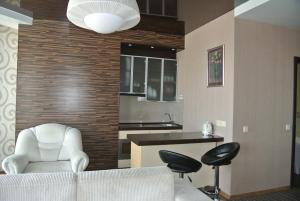 a living room with a white chair and a kitchen at Panoramic view apartment Poznyaky in Kyiv