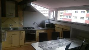 una cucina con tavolo e lavandino e due finestre di M&F APARTAMENT JEPILOR a Braşov