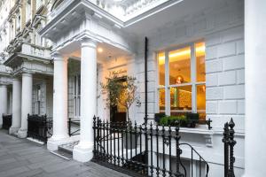 ein weißes Haus mit einem schwarzen Zaun davor in der Unterkunft Park Avenue J Hotel London Hyde Park in London
