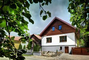 a white house with a wooden roof at Apartmany Izbica in Červený Kláštor
